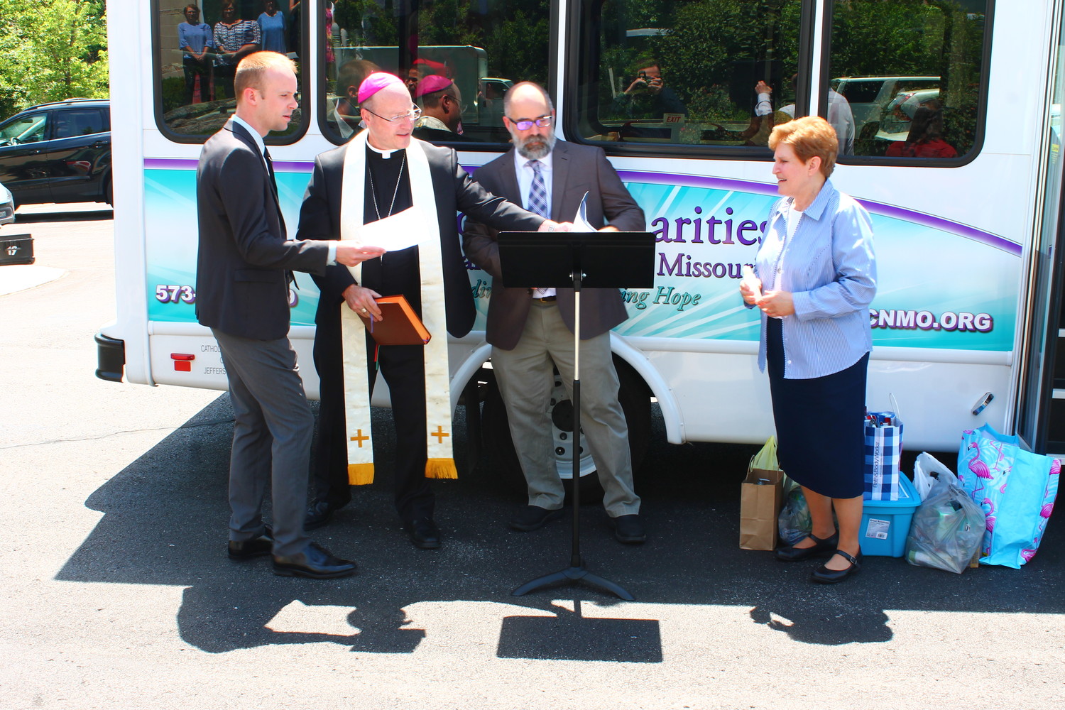 Jake Seifert, left, mission advancement director for Catholic Charities of Central and Northern Missouri (CCCNM); Executive Director Dan Lester; and Sister Kathleen Wegman SSND, chancellor of the Jefferson City diocese, join Bishop W. Shawn McKnight at a ceremony to bless CCCNM’s new Mobile Resource Bus outside the Alphonse J. Schwartze Memorial Catholic Center on June 6.